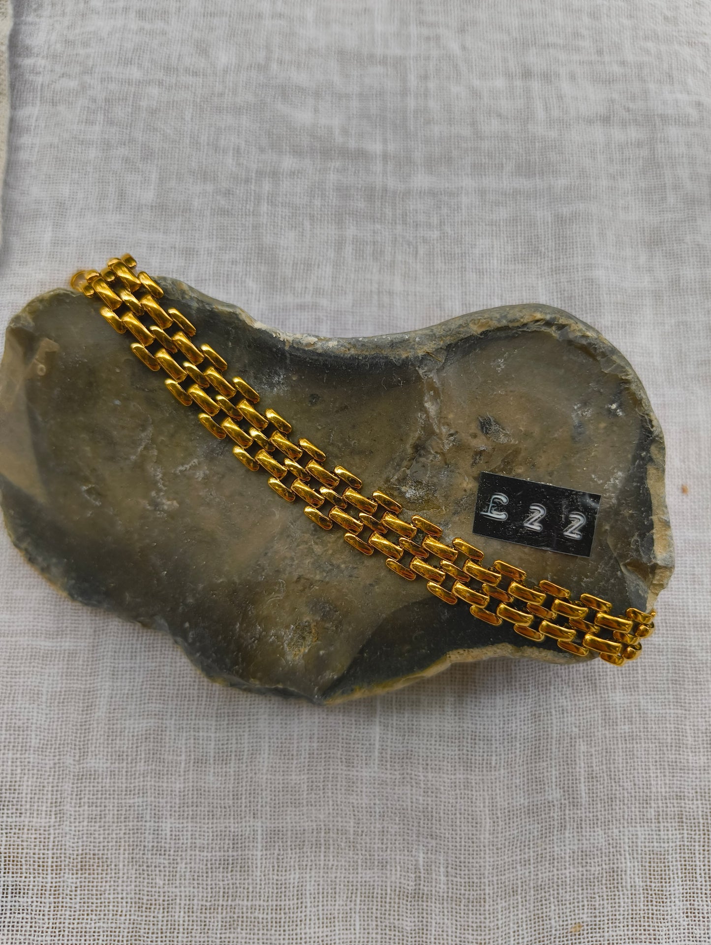 Gold chain on a stone object with a label on a gray fabric background