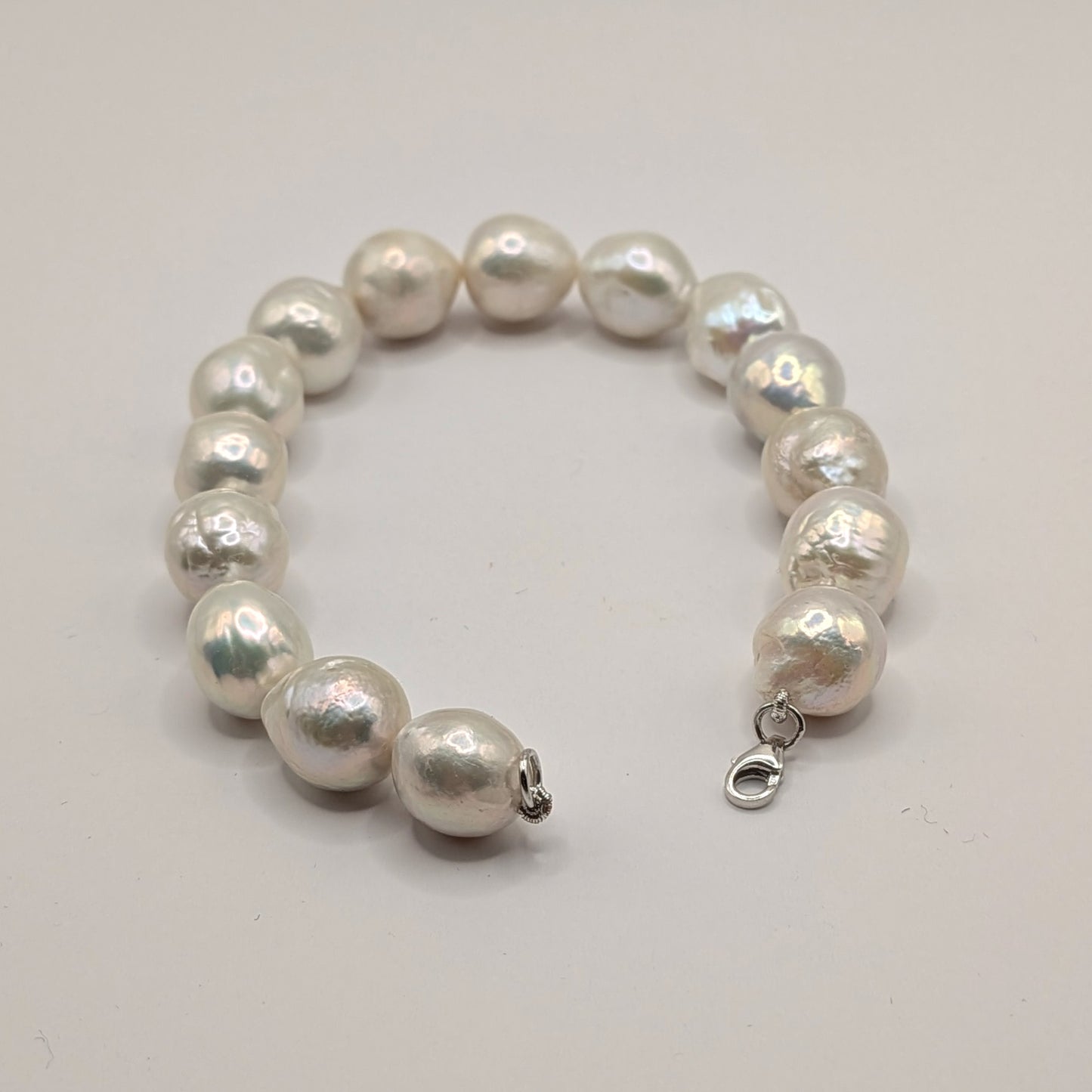 Pearl bracelet with silver clasp on a light gray background