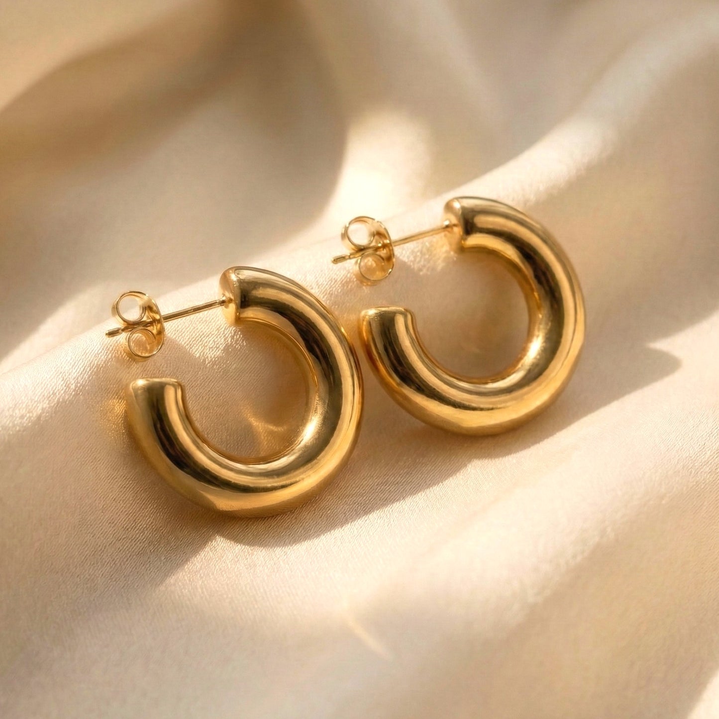 Gold hoop earrings on a beige fabric background