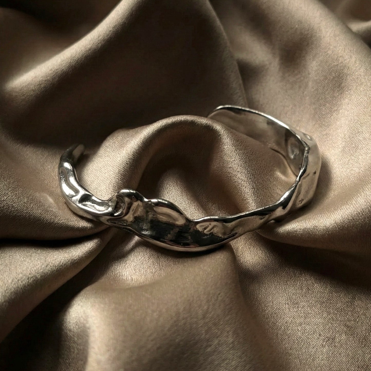 Silver plated molten cuff on brown silk background