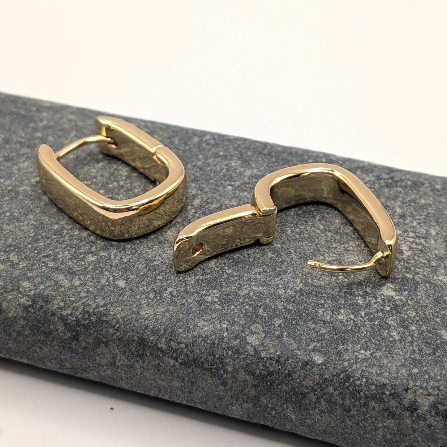 Gold hoop earrings on a textured gray surface