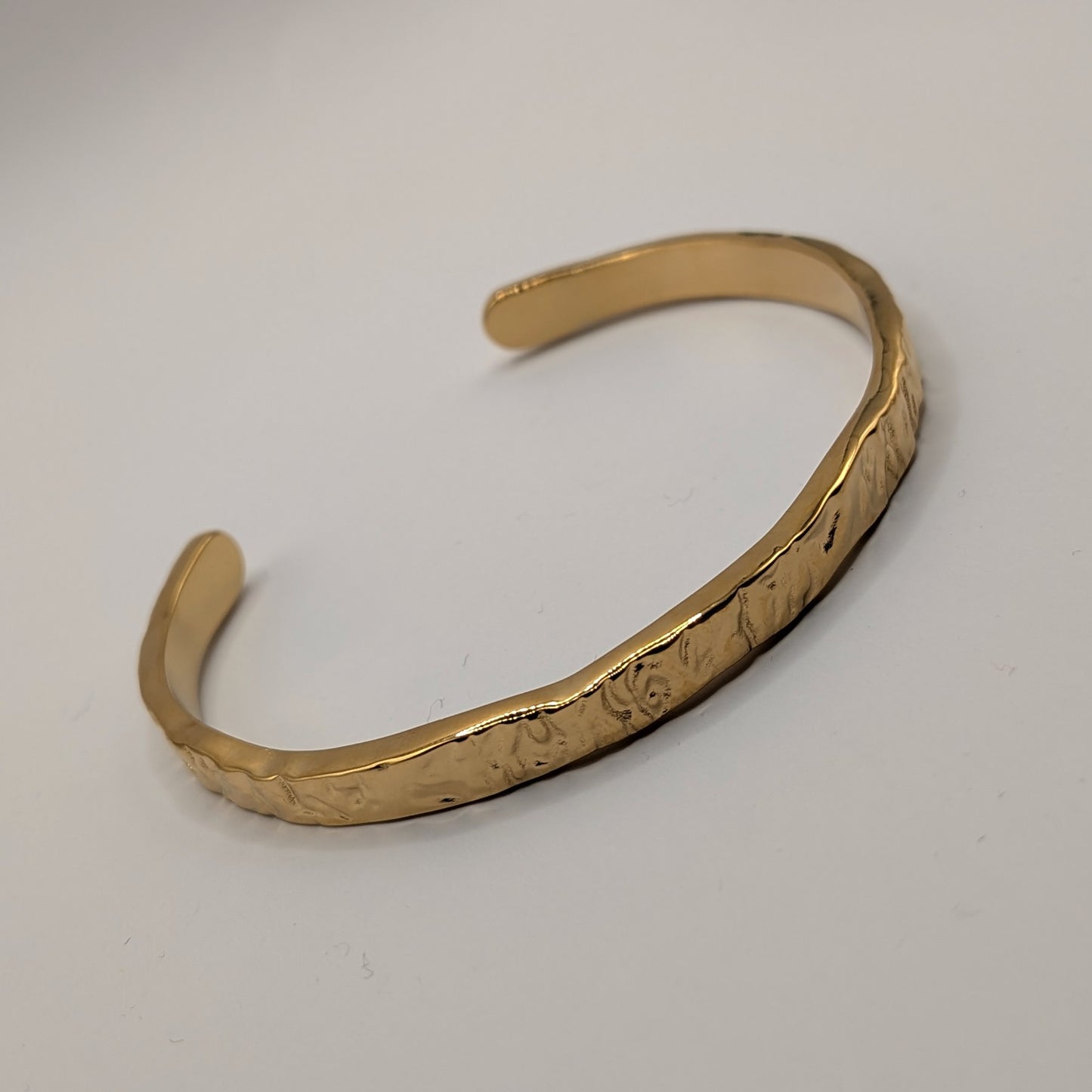 Gold bracelet on a light gray background