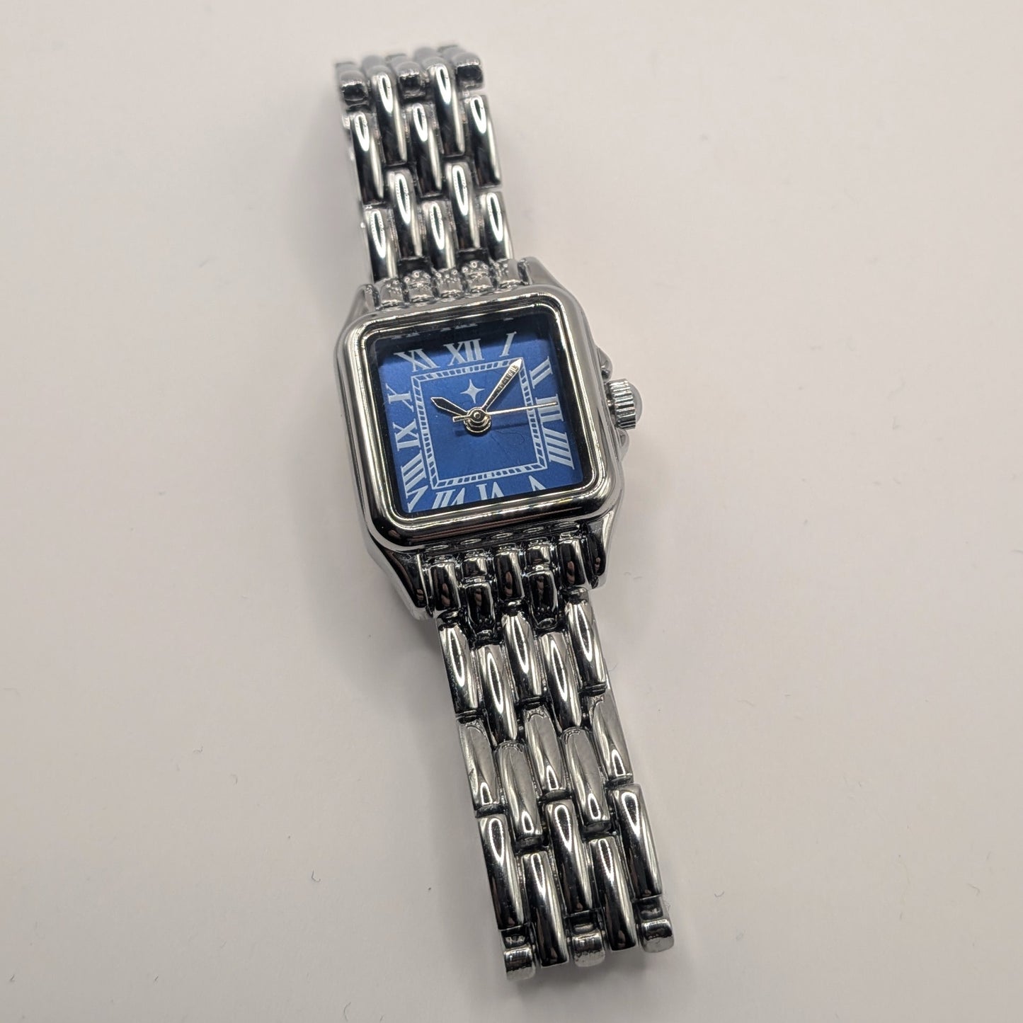 Silver watch with a blue face on a light gray background