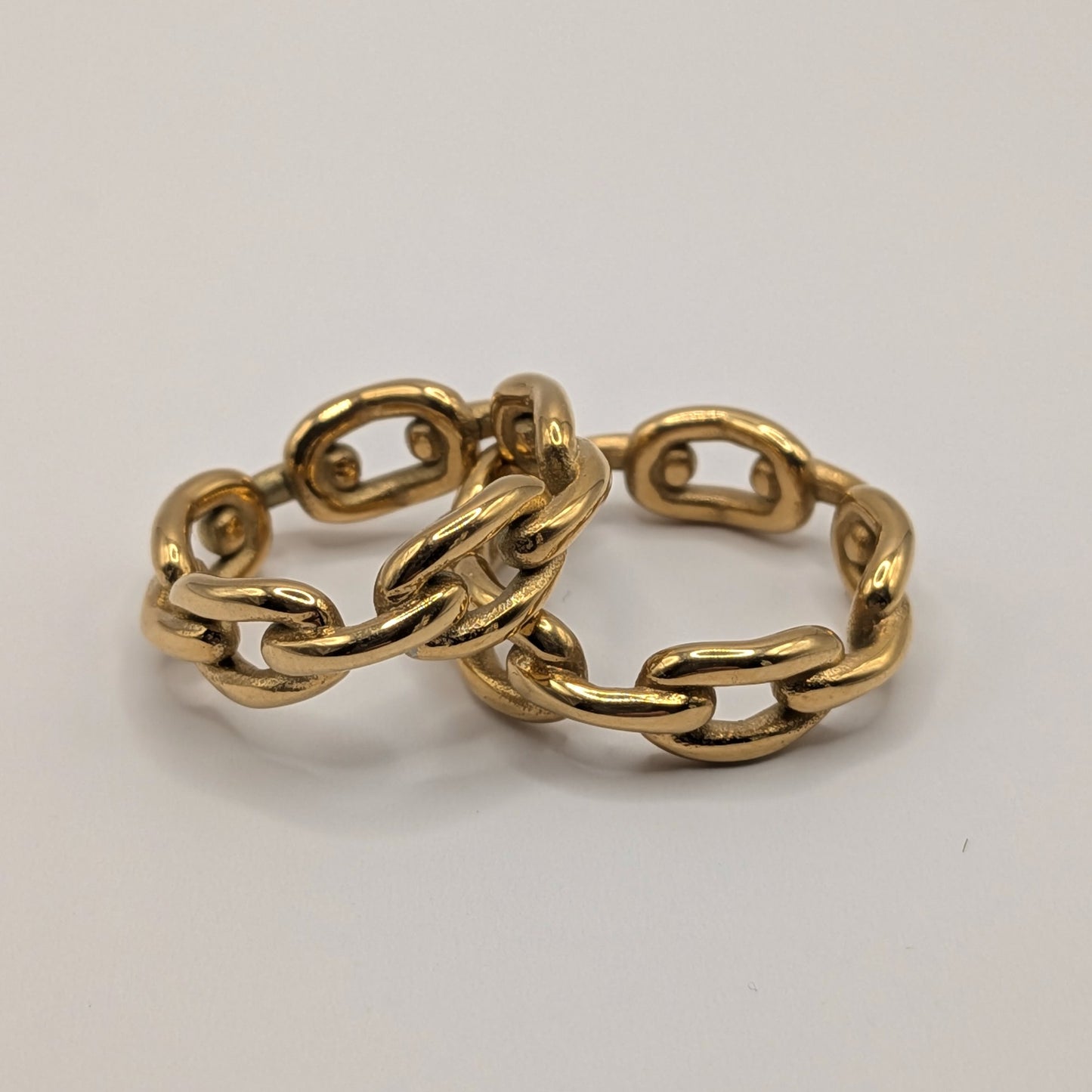 Gold chain-style ring on a light gray background