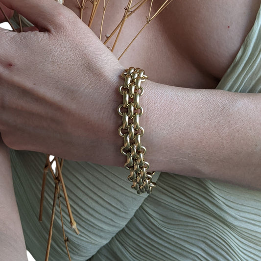Gold chain bracelet on a wrist with a soft background