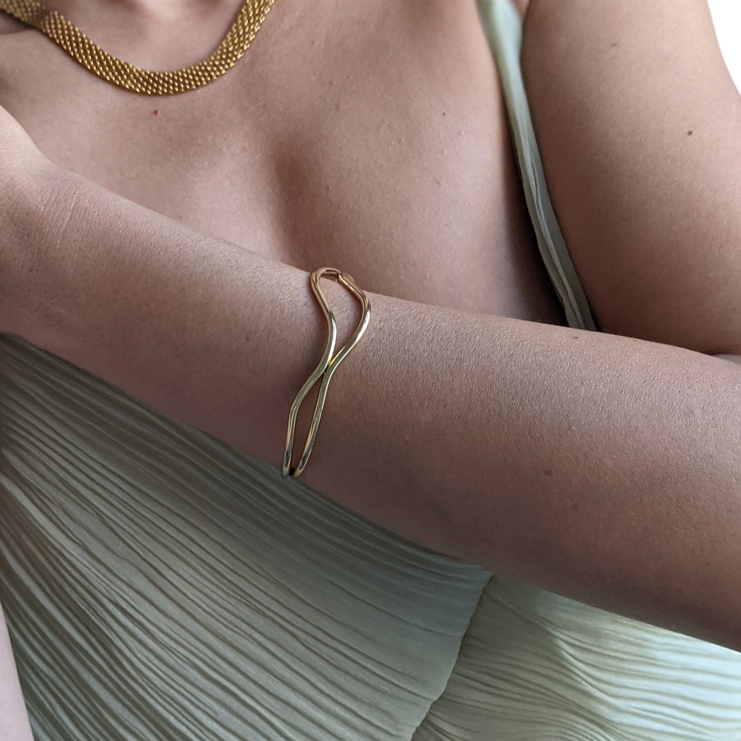 Gold bracelet on a person's wrist with a neutral background