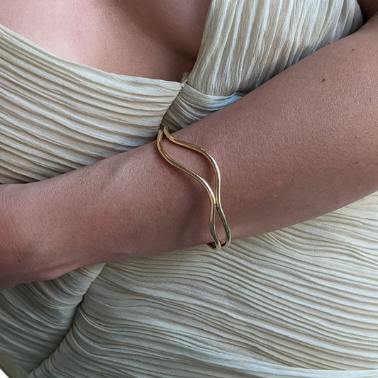 Gold bracelet on a person's wrist with a neutral background