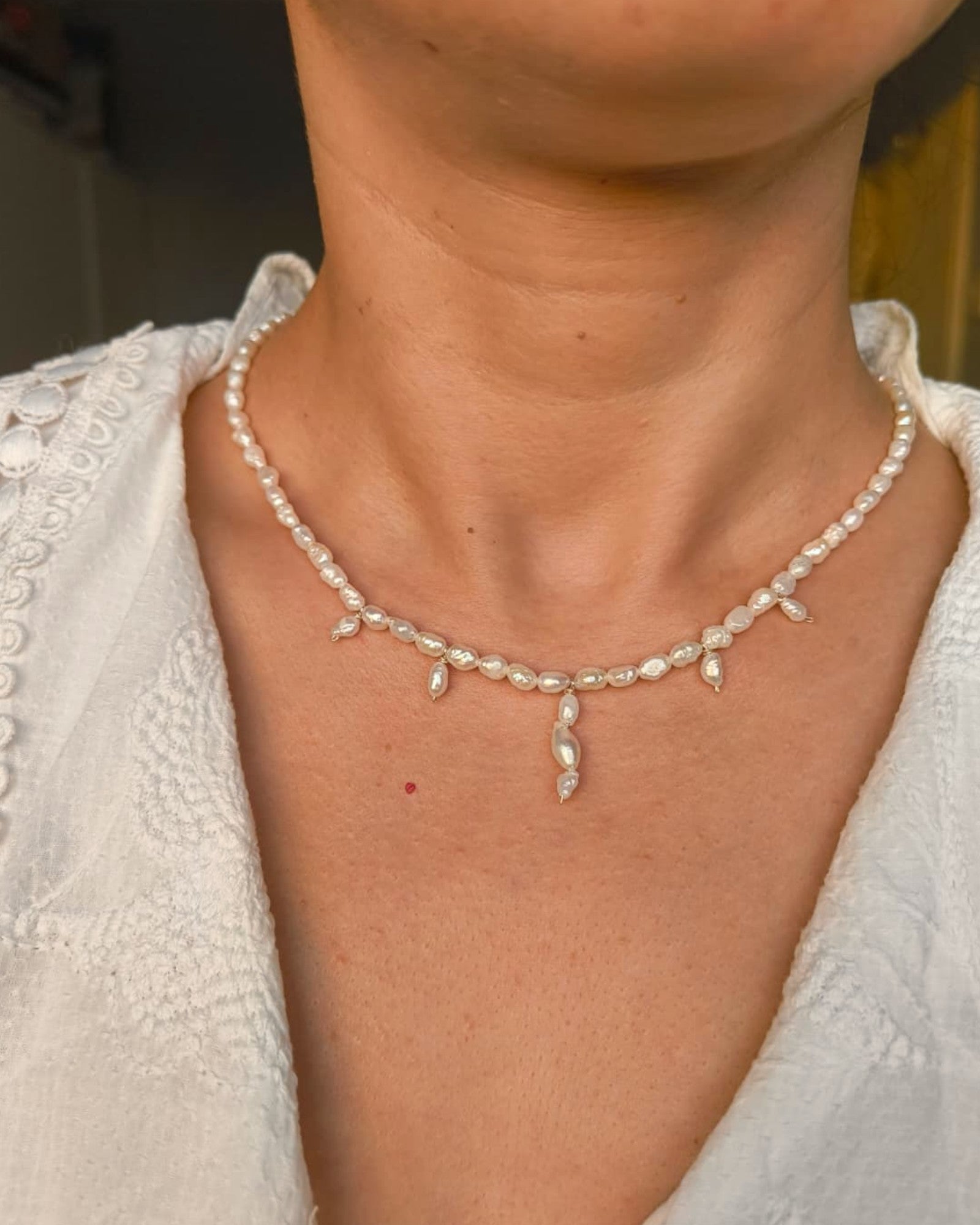 Pearl necklace worn by a person with a blurred background