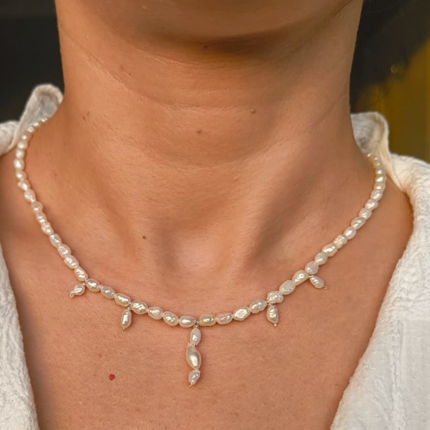 Pearl necklace worn by a person with a blurred background