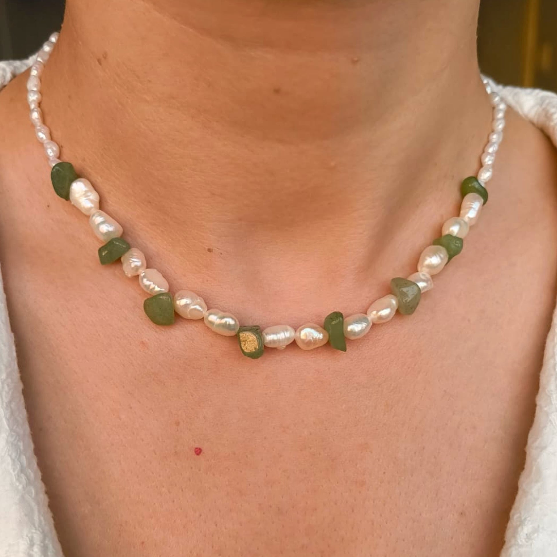 Necklace with green and pink beads worn by a person