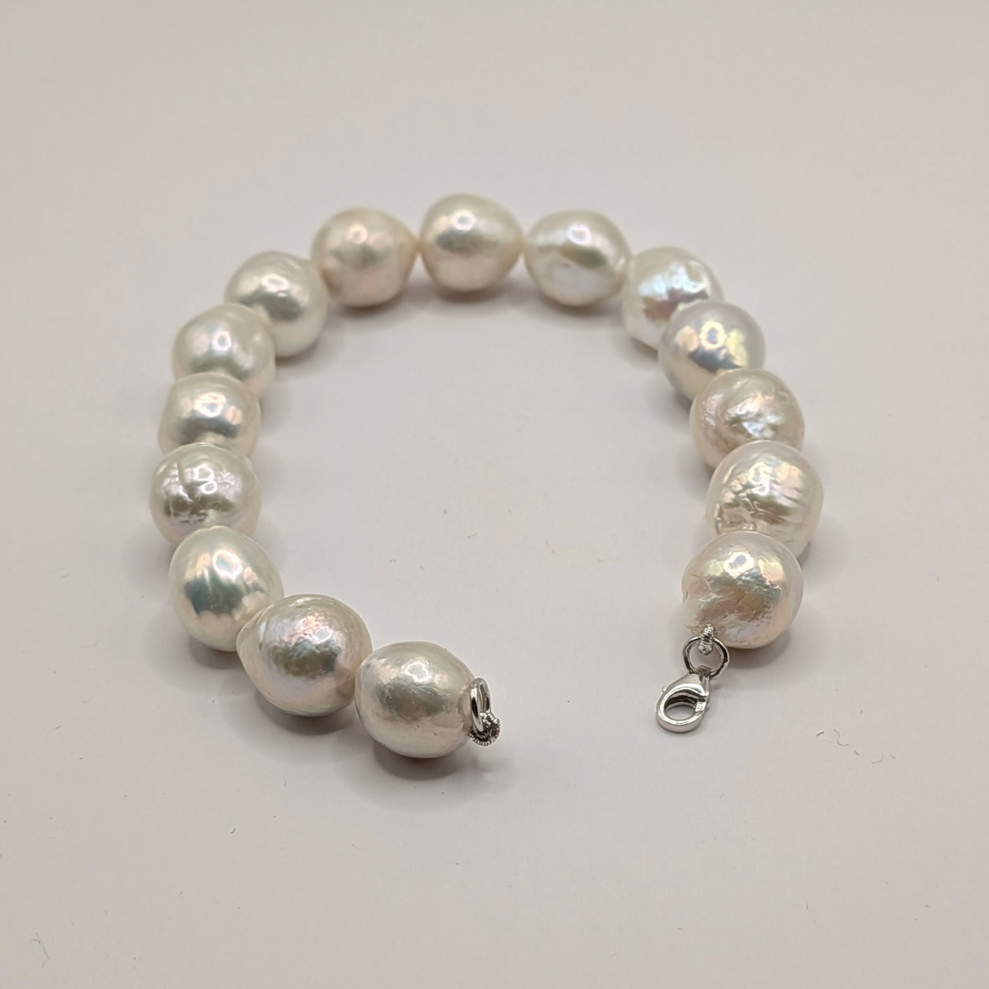 Pearl bracelet with silver clasp on a light gray background
