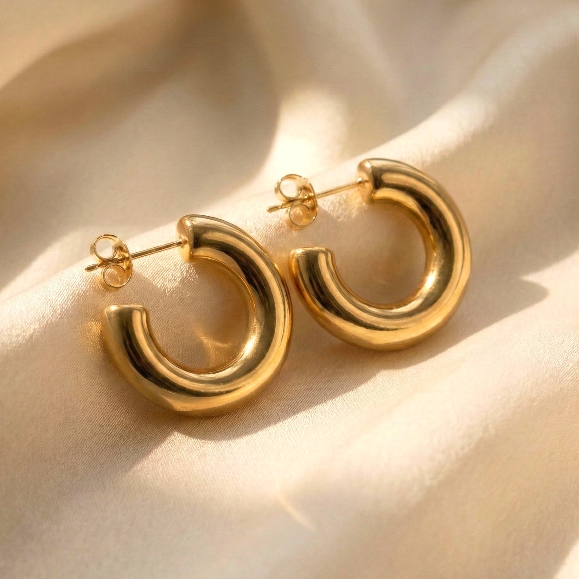 Gold hoop earrings on a beige fabric background