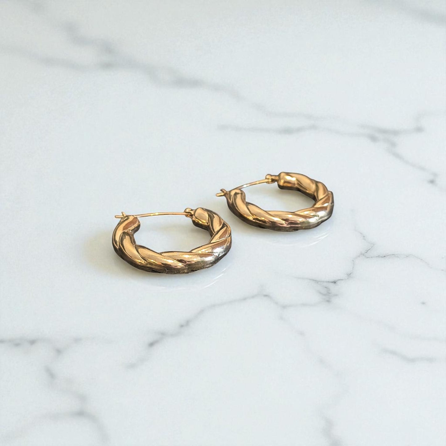Gold hoop earrings on a marble surface