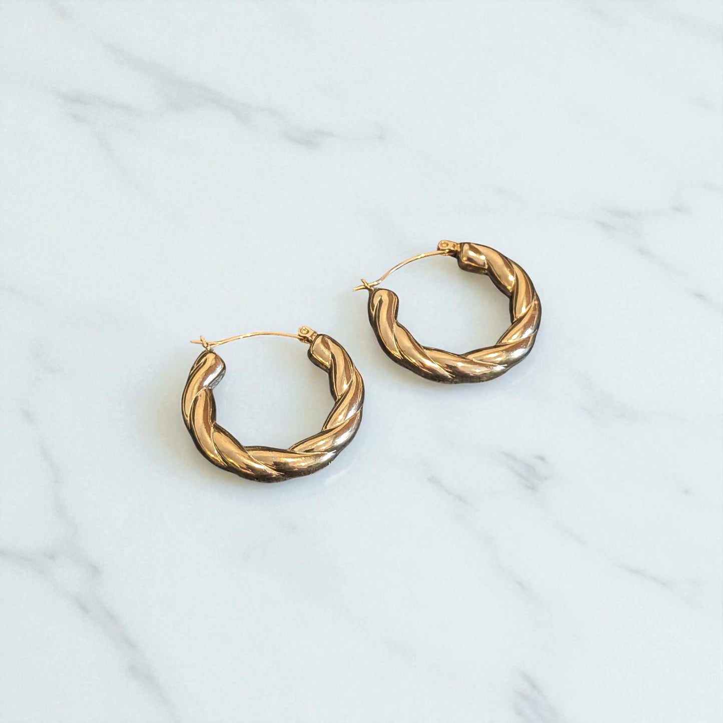 Pair of gold hoop earrings on a light gray background
