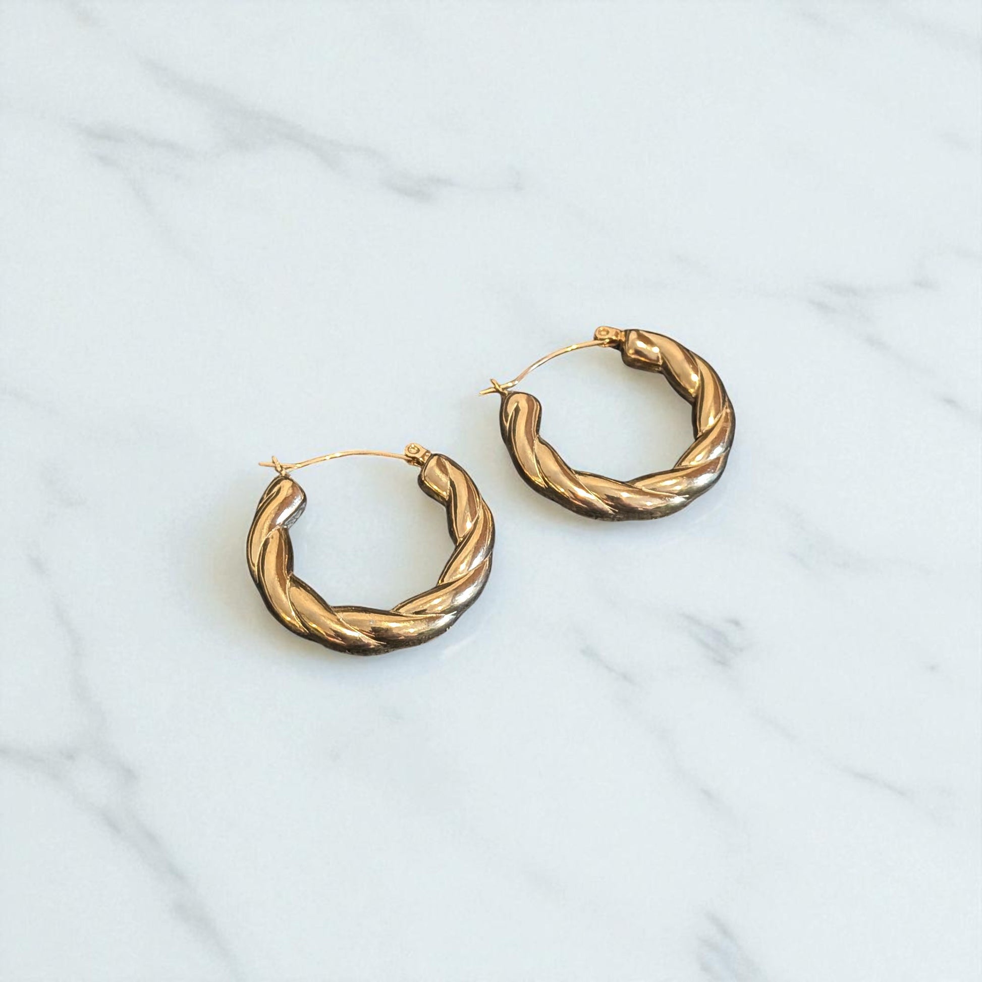 Pair of gold hoop earrings on a light gray background