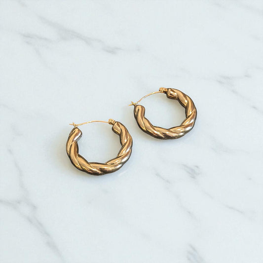 Pair of gold hoop earrings on a light gray background