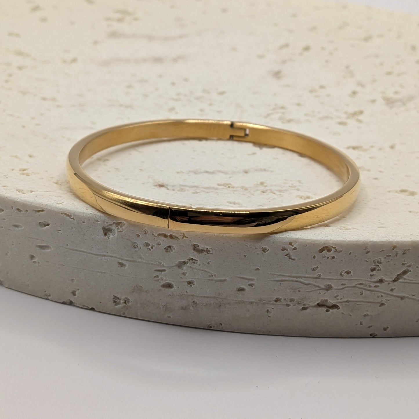 Gold bracelet on a textured stone surface