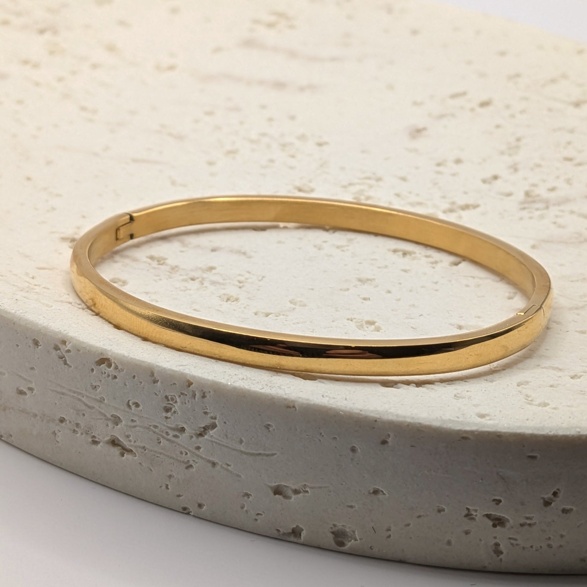 Gold plated bracelet on a textured stone surface