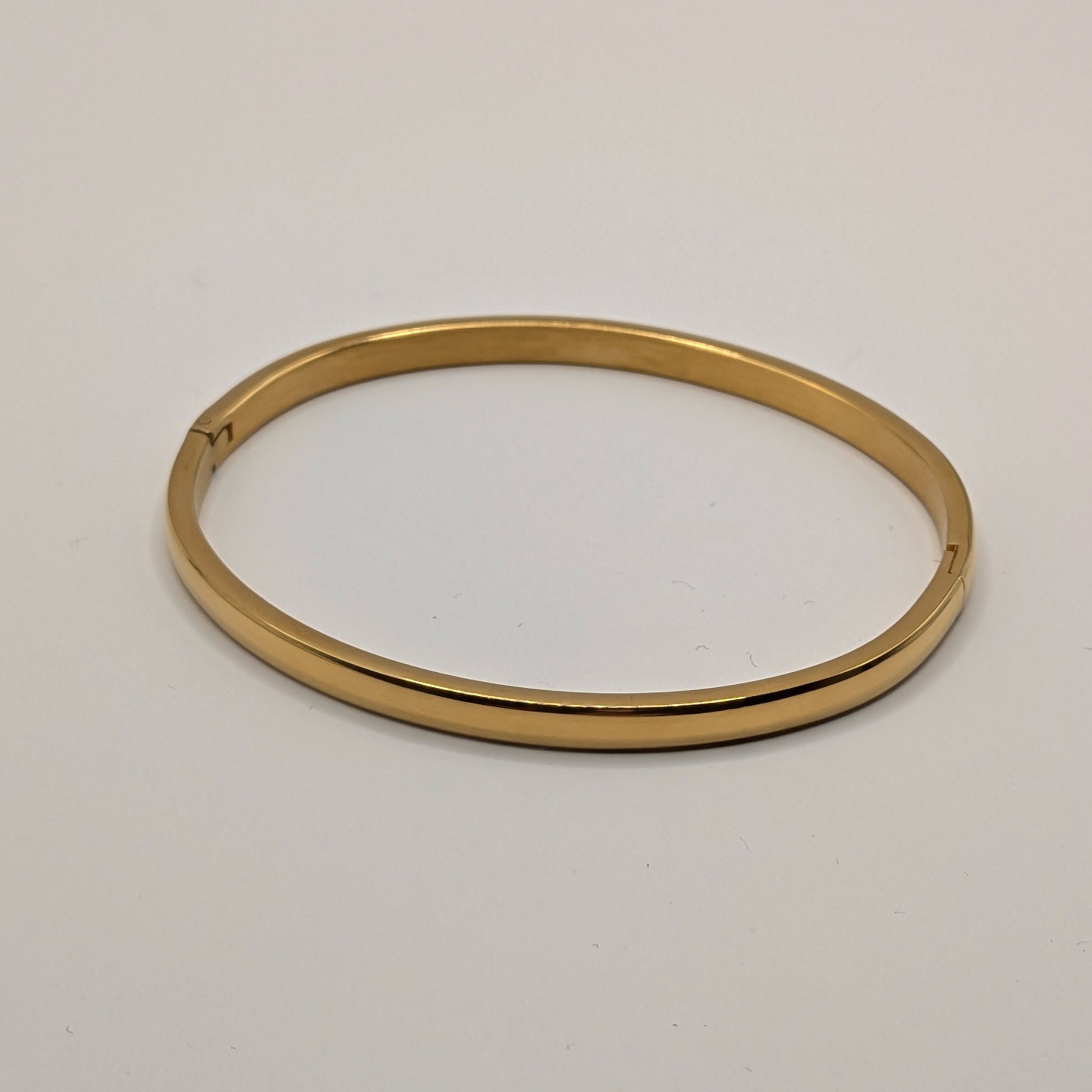 Gold plated bangle on a light gray background