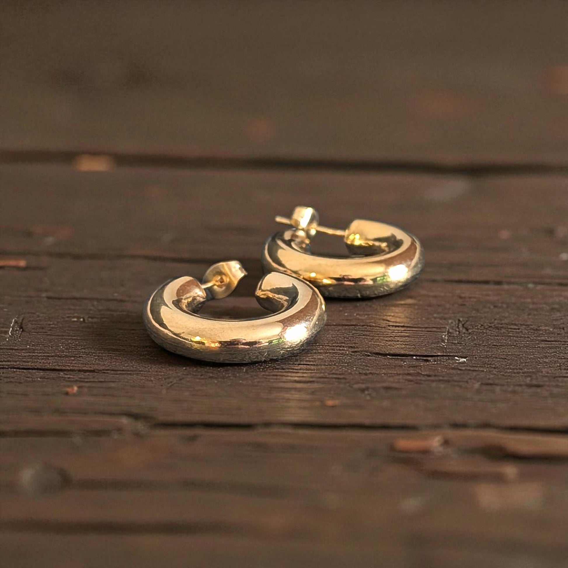Gold hoop earrings on a wooden surface