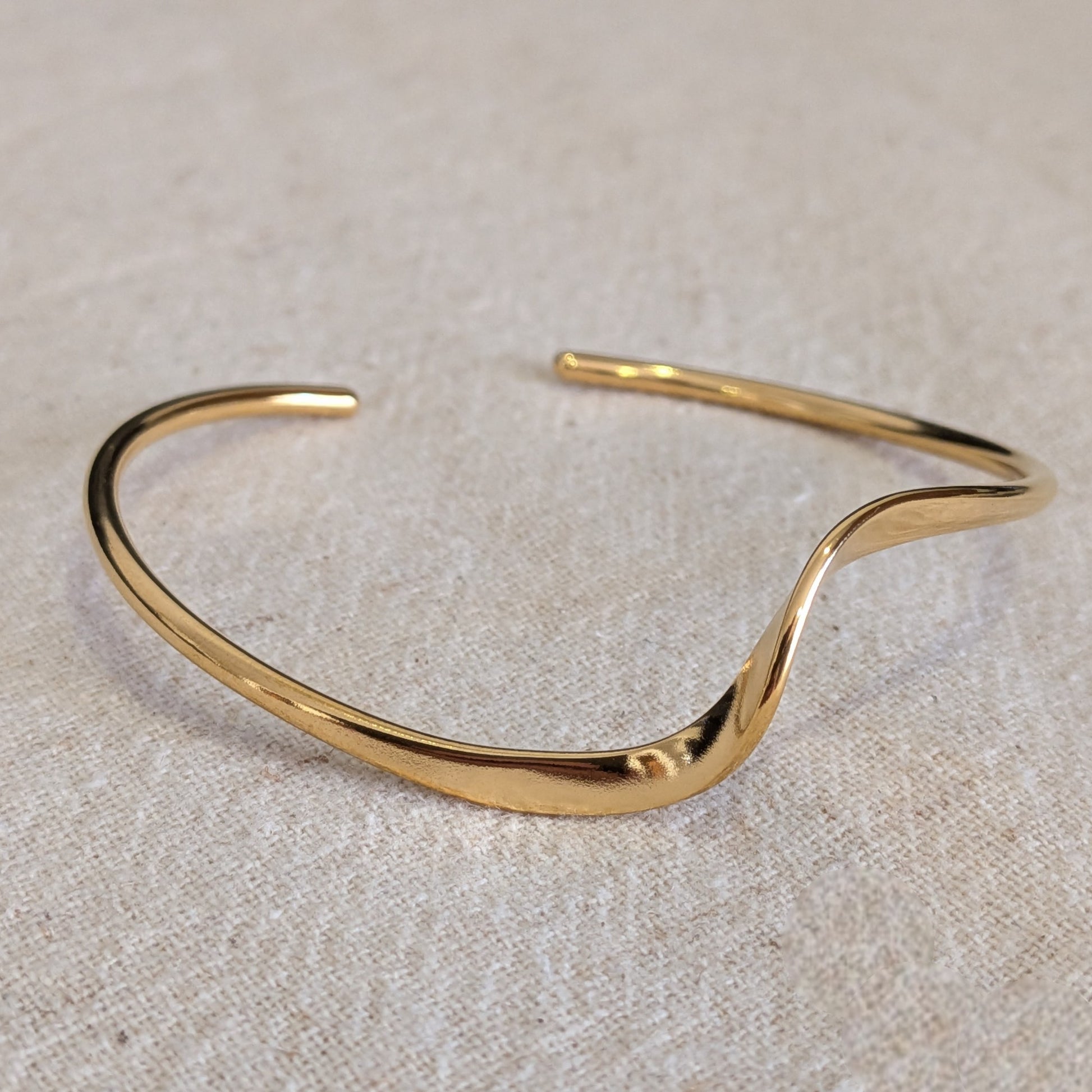 18k Gold plated bangle on a beige fabric background