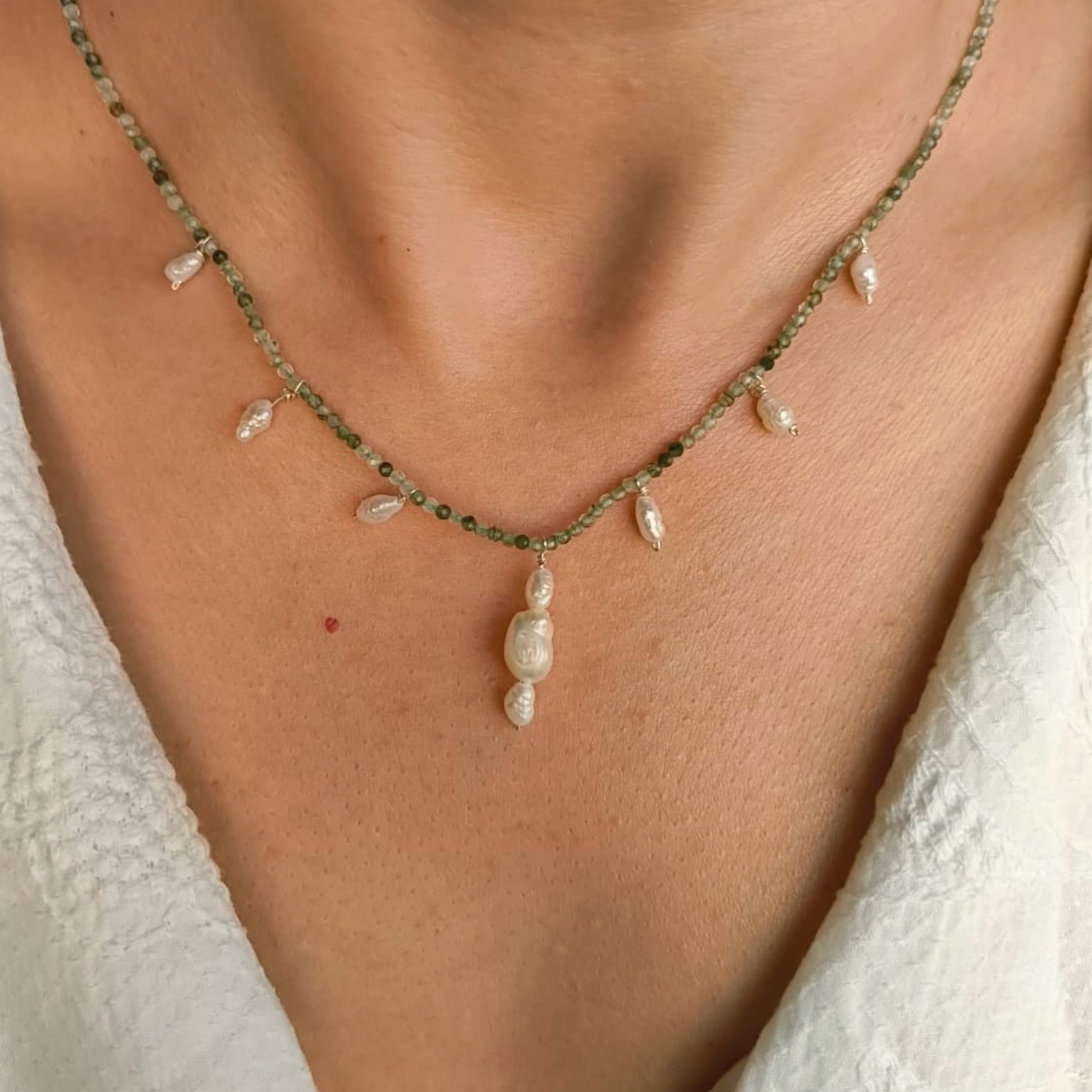 Necklace with pearls on a person's neck against a neutral background