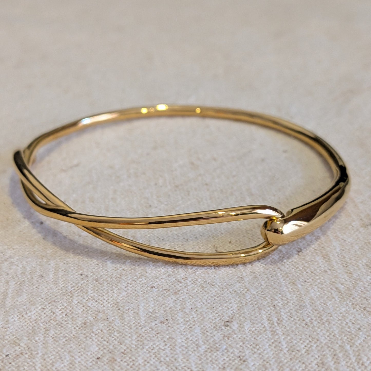 Gold bangle on a beige fabric background