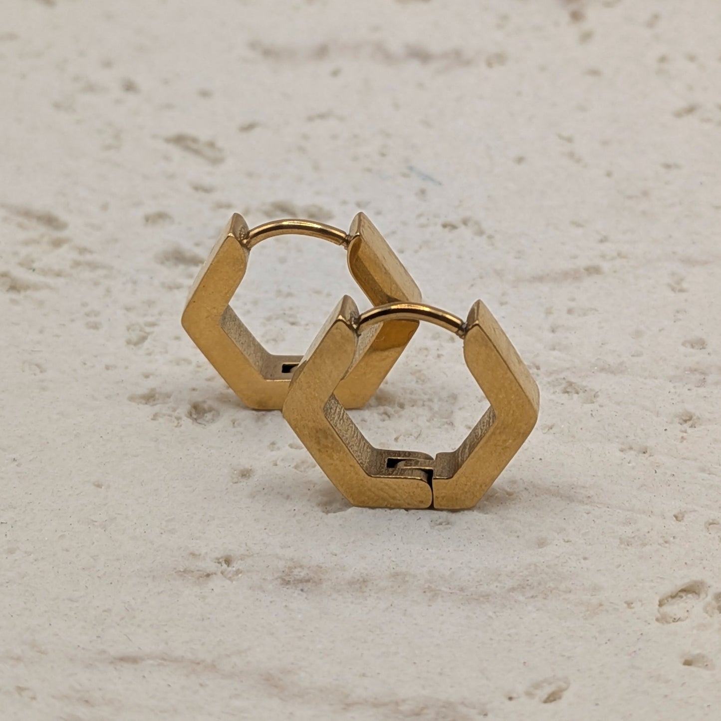 Gold hoop earrings on a light beige surface