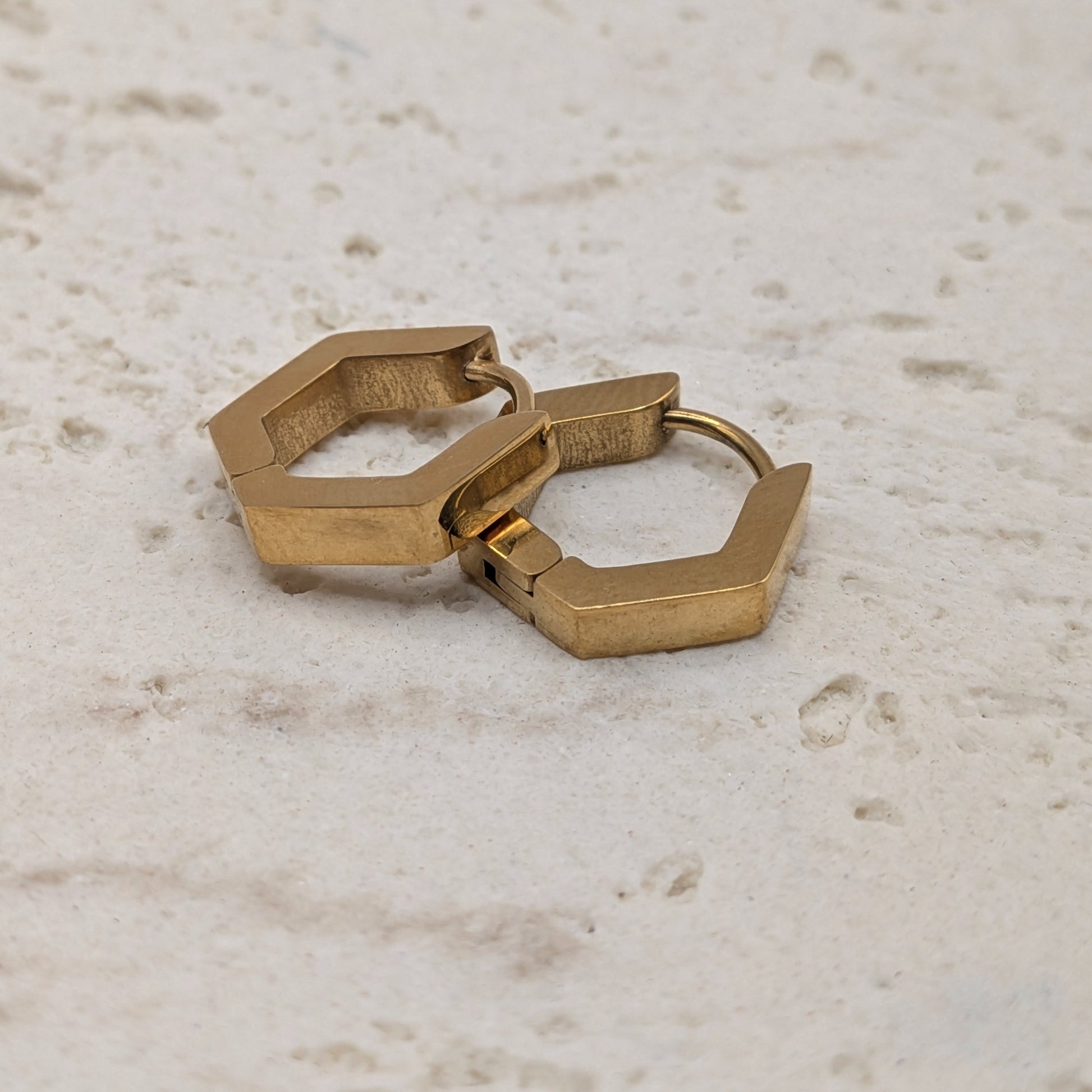 Pair of gold hoop earrings on a light marble background