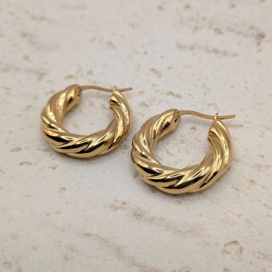 Gold hoop earrings on a light marble background