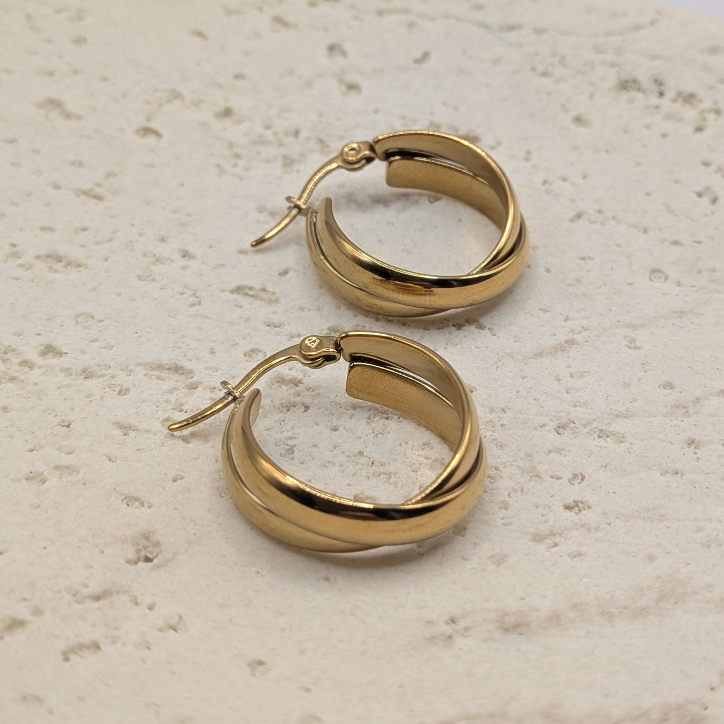 Pair of gold hoop earrings on a light stone surface