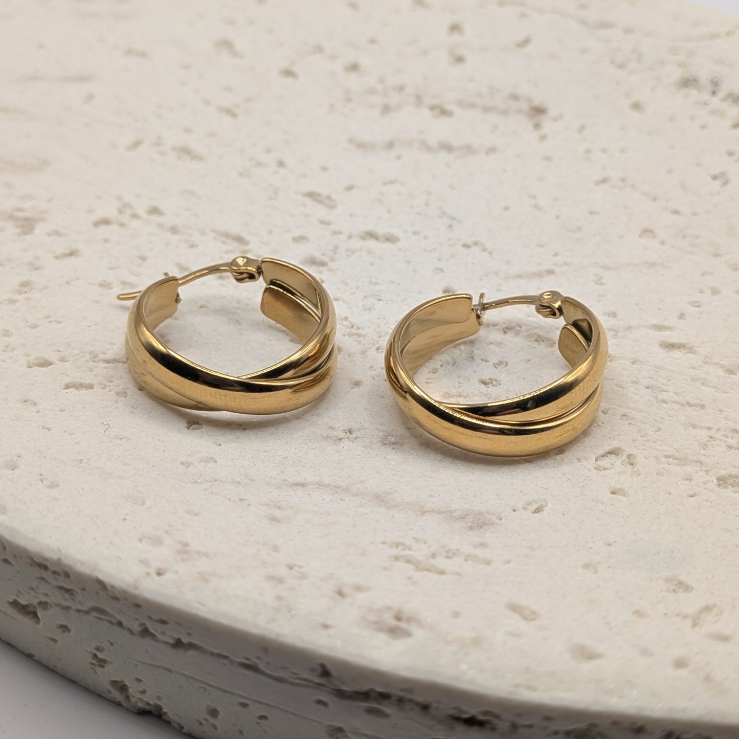 Pair of gold hoop earrings on a light stone surface