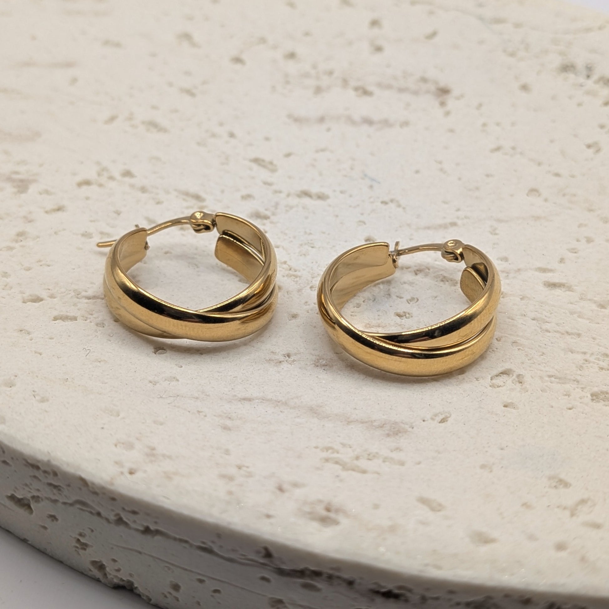 Pair of gold hoop earrings on a light stone surface