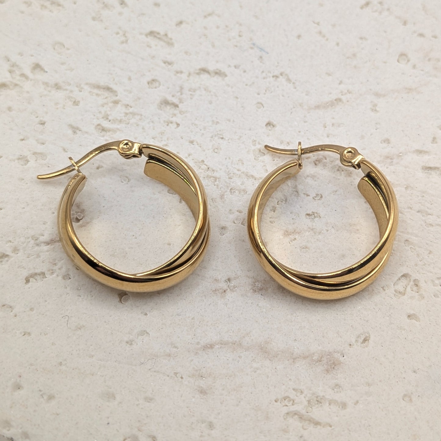 Gold hoop earrings on a light stone surface
