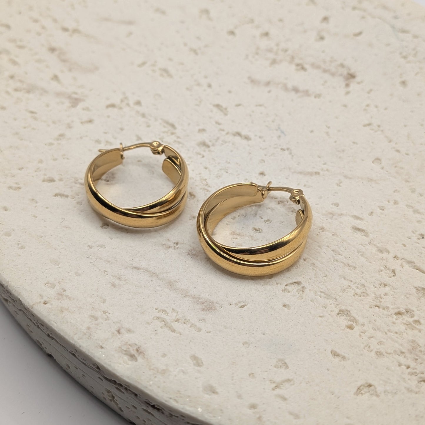Gold hoop earrings on a light stone surface