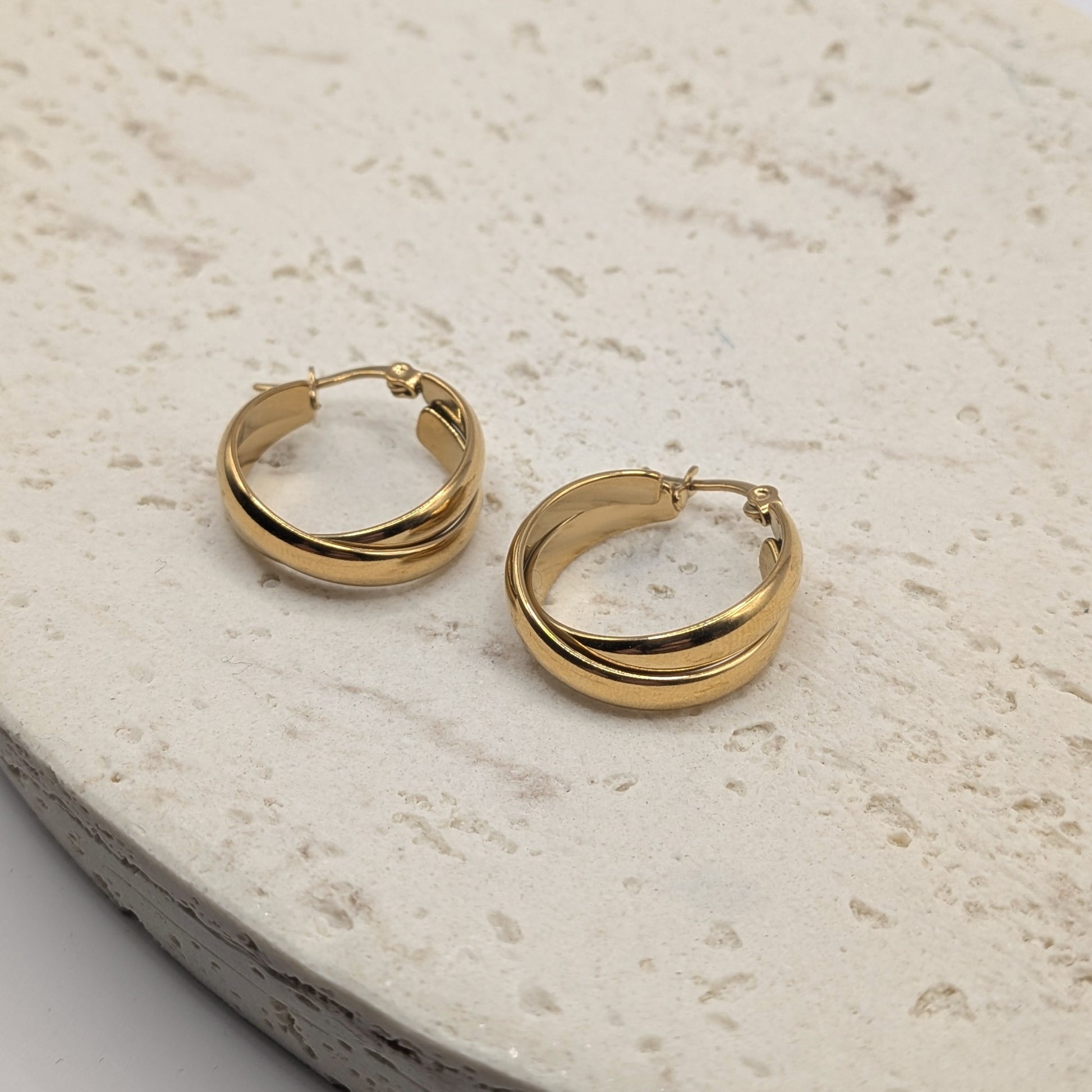 Gold hoop earrings on a light stone surface