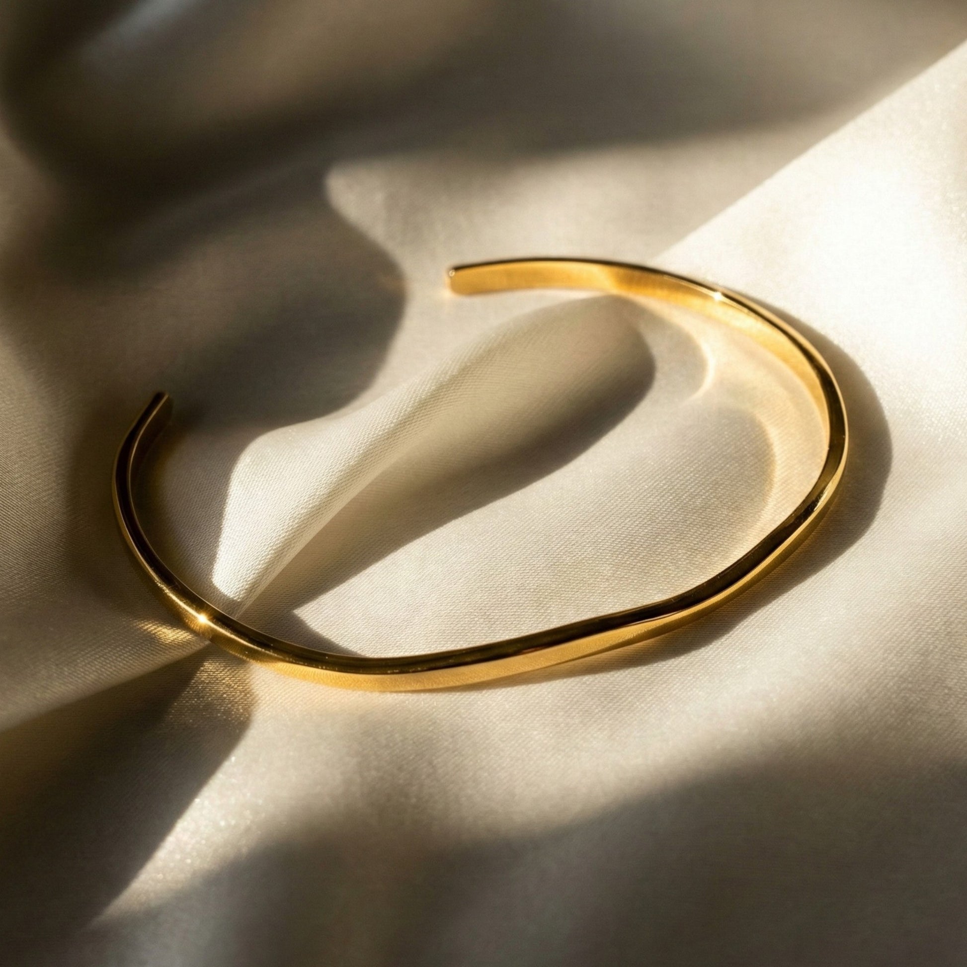 Gold plated bangle on silk background