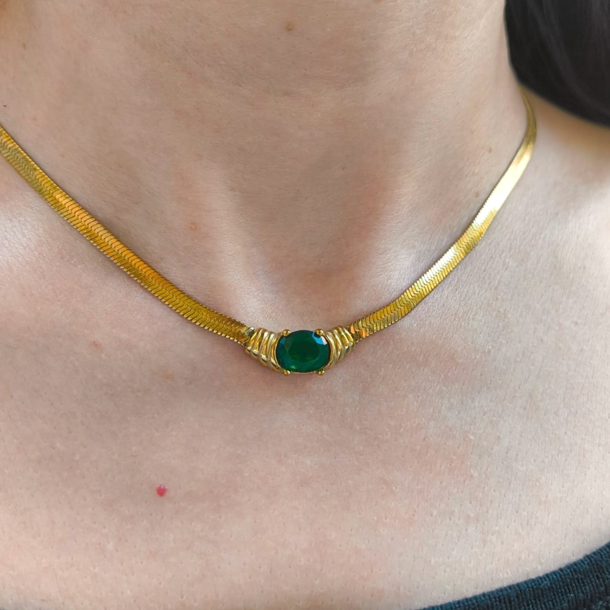 Gold necklace with a green gemstone on a person's neck