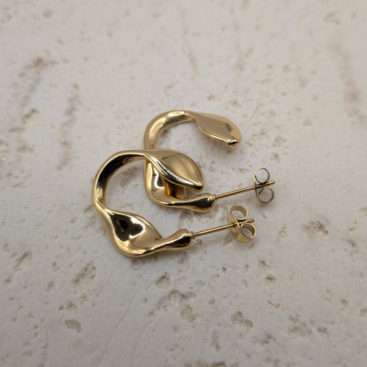 Gold hoop earrings on a light beige surface