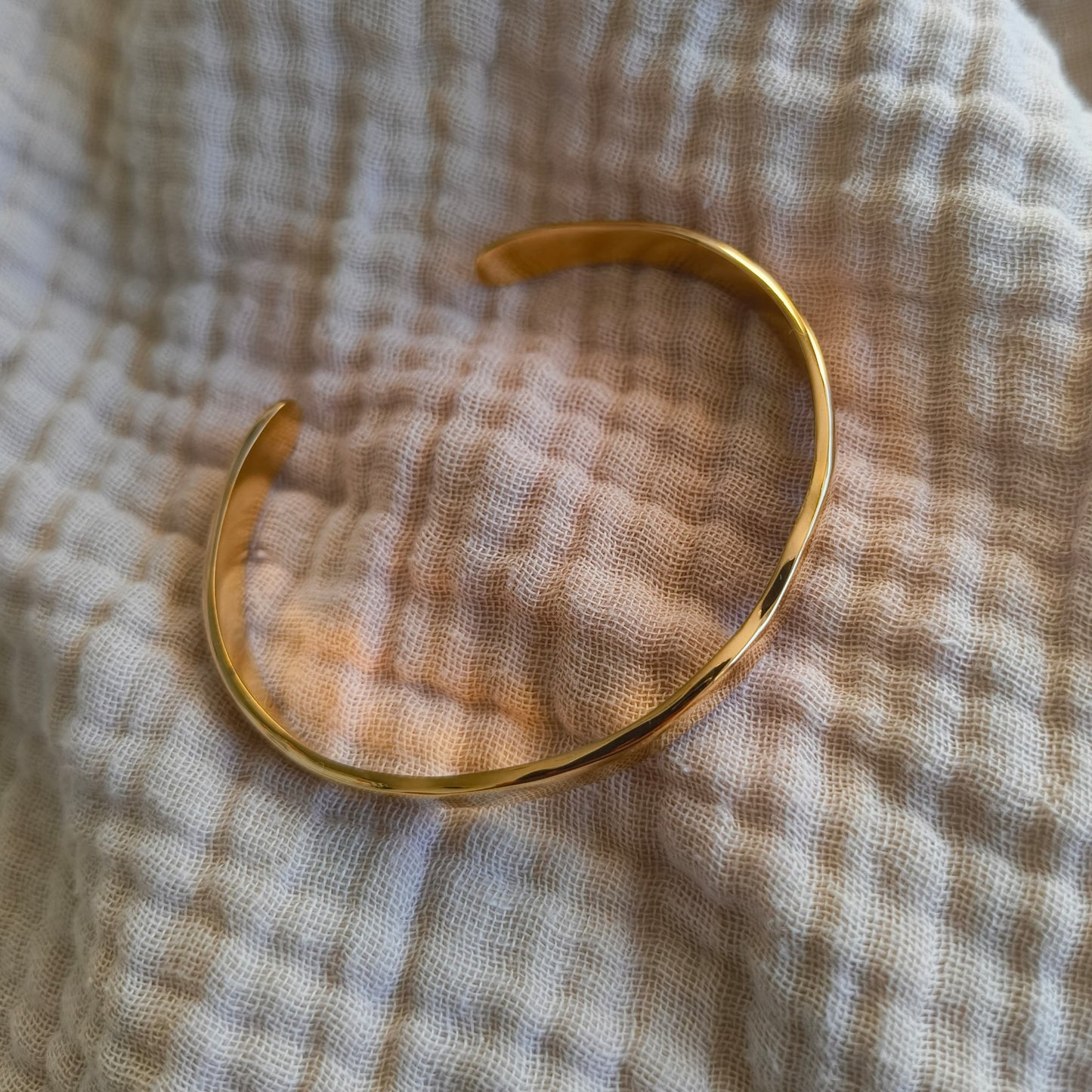 Gold bracelet on a textured beige fabric background