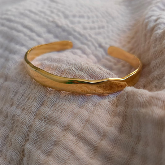 Gold bracelet on a textured beige fabric background