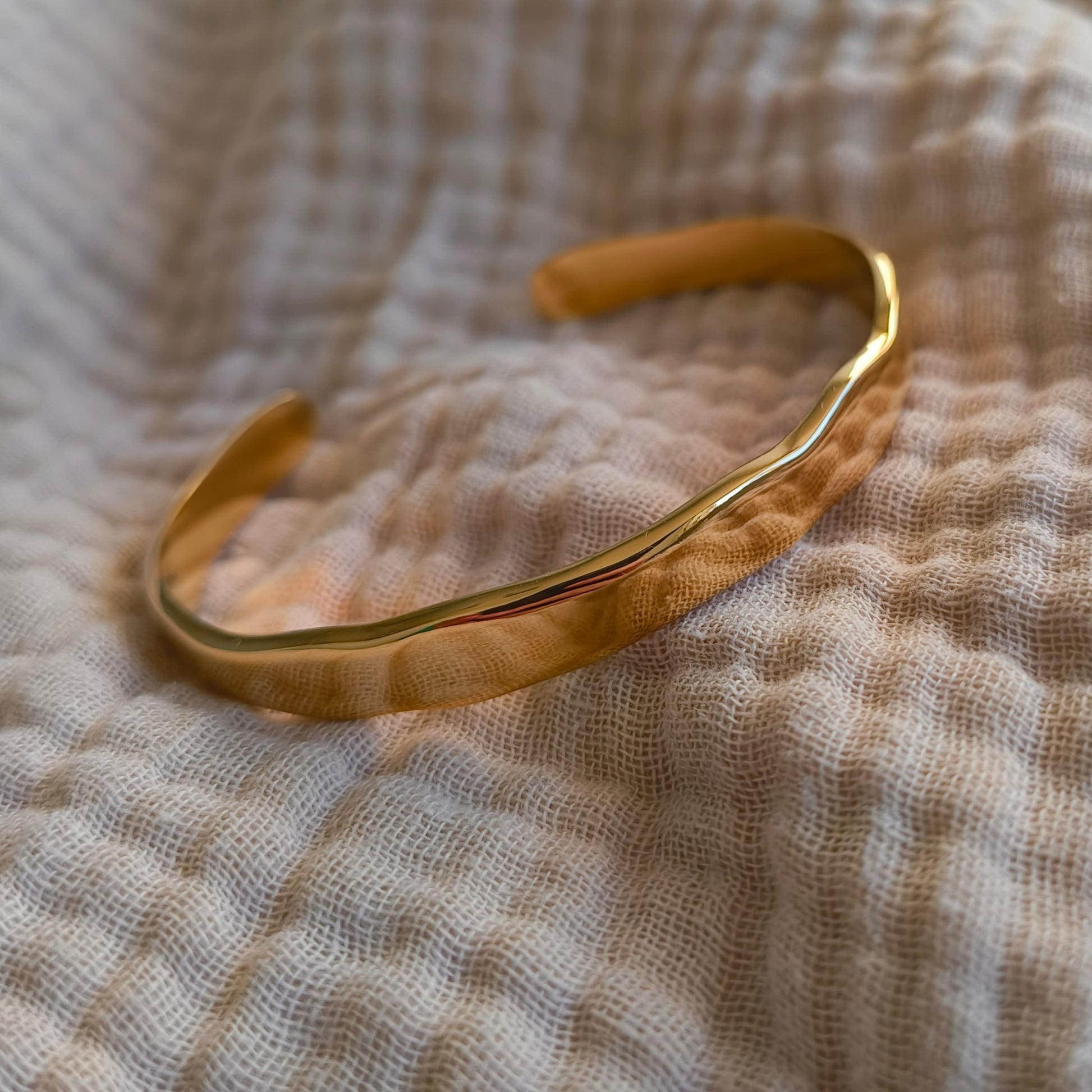 Gold bracelet on a textured beige fabric background