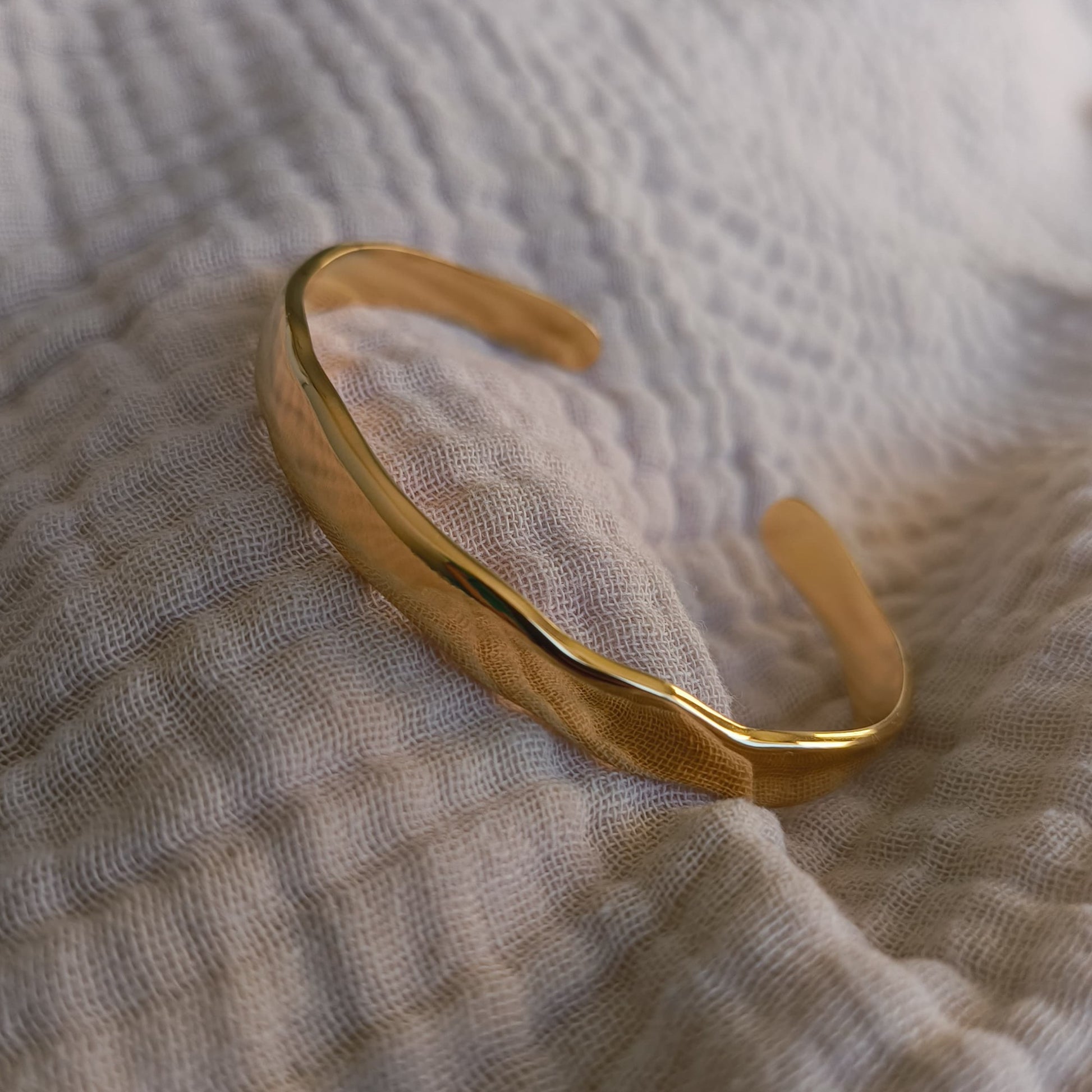 Gold bracelet on a textured fabric surface