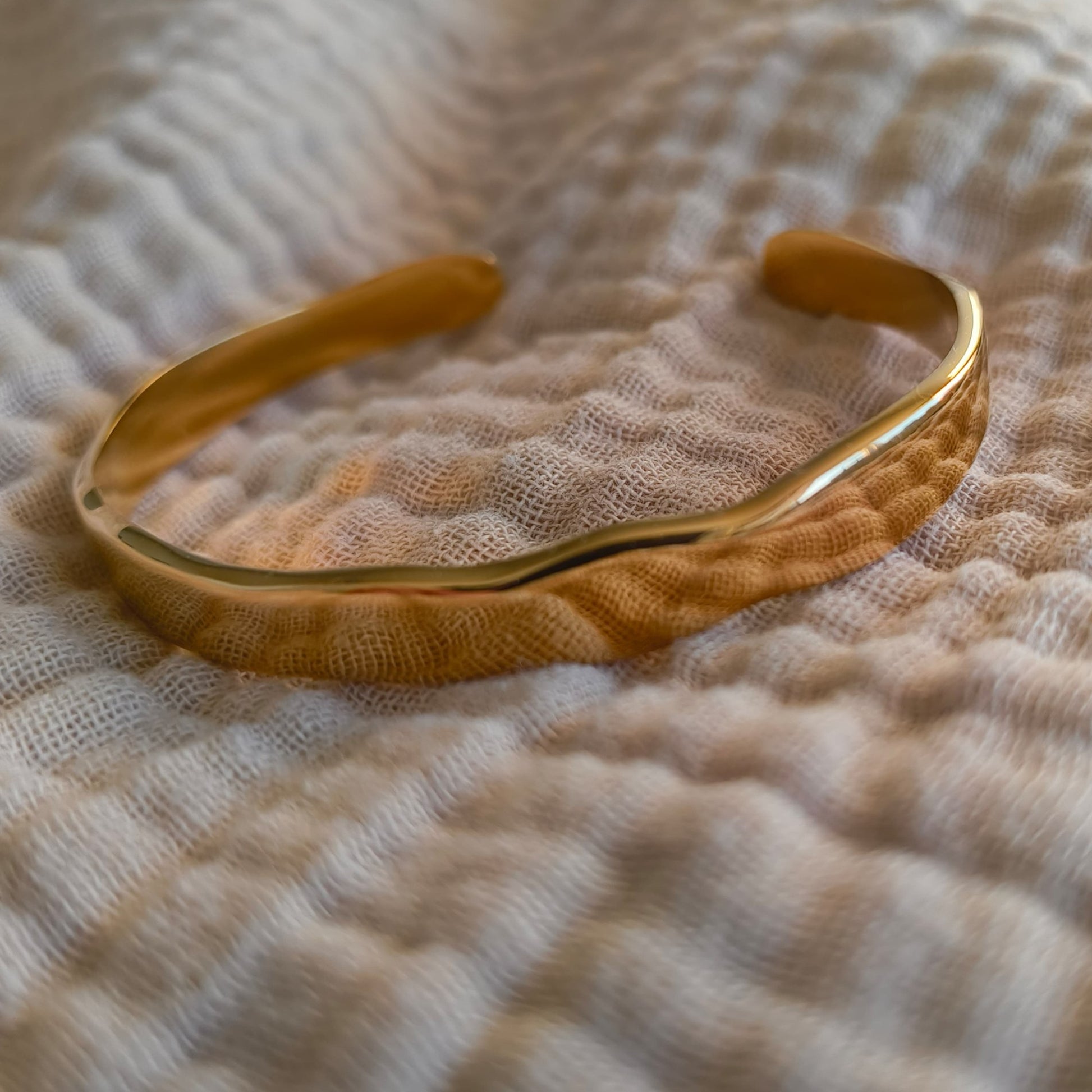 Gold bracelet on a textured beige fabric background