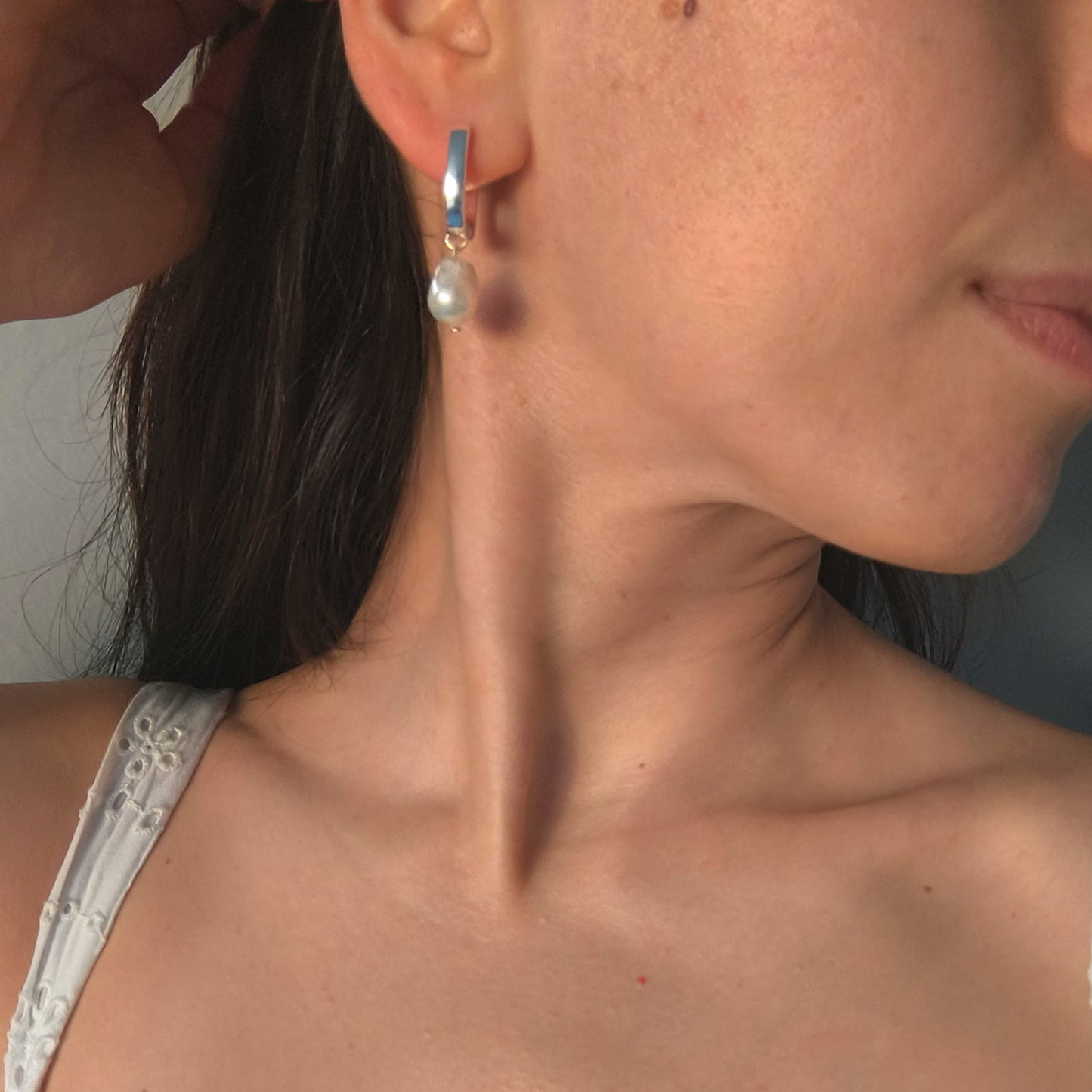 Close-up of a woman wearing a pearl earring with a blurred background