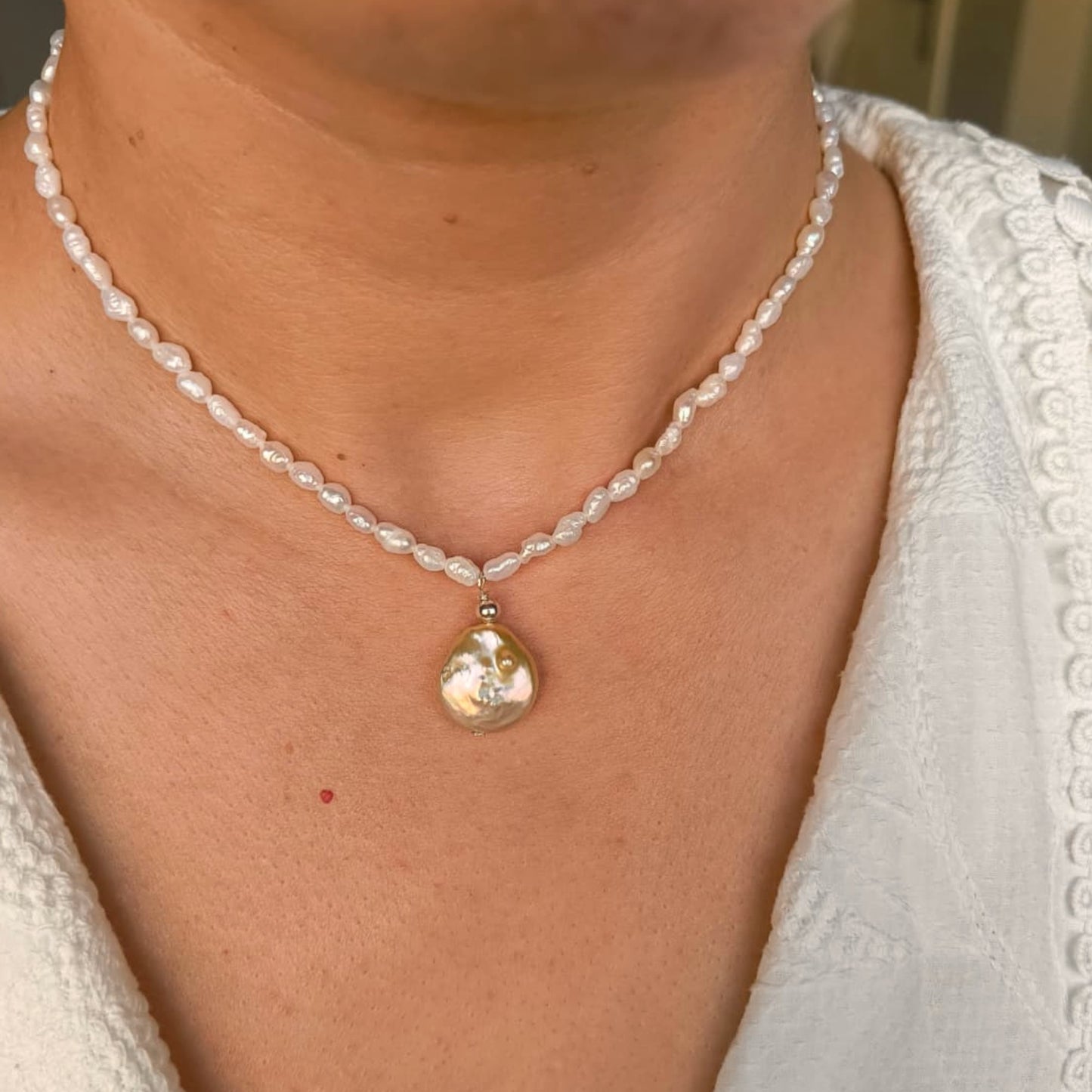 Pearl necklace with a large pendant worn by a person