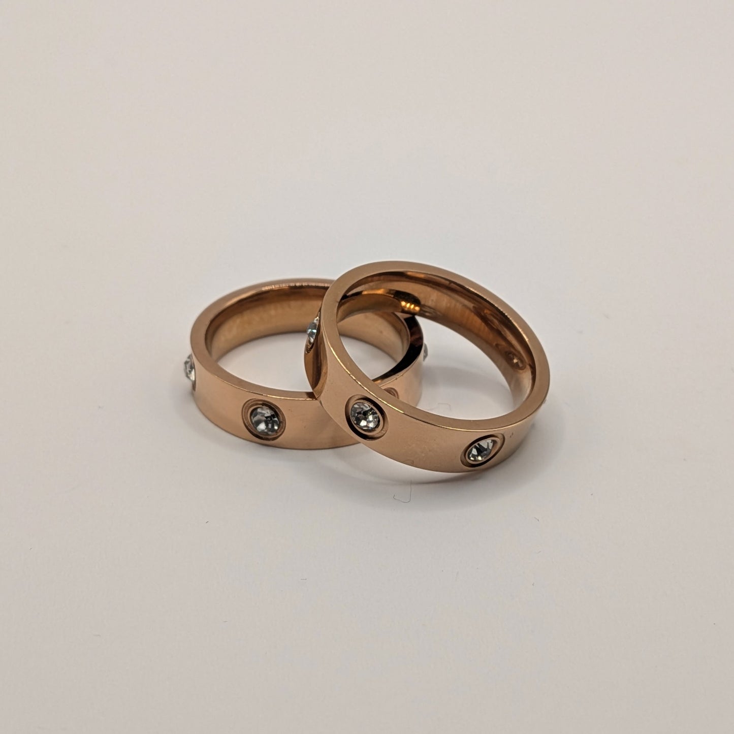 Two rose gold rings with embedded stones on a light gray background