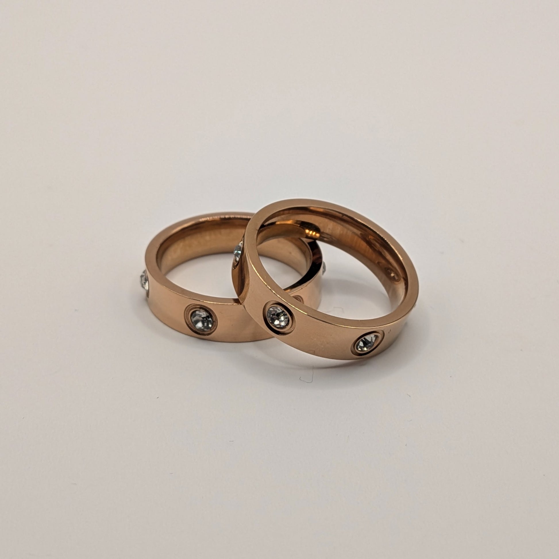 Two rose gold rings with embedded stones on a light gray background
