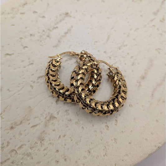 Gold hoop earrings on a light stone surface