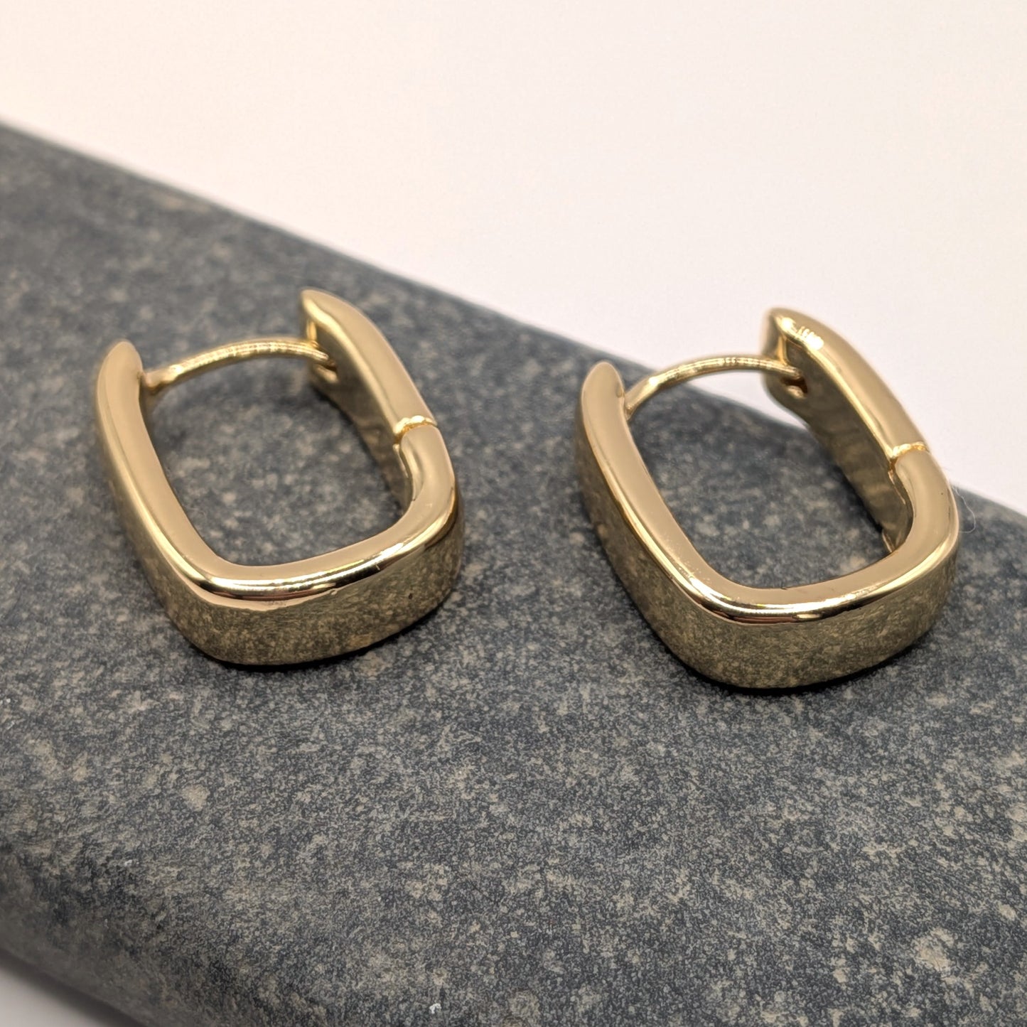 Gold hoop earrings on a textured gray surface